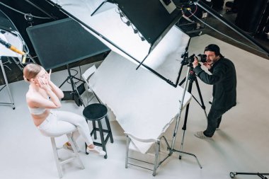 Stüdyoda spot ışıklarıyla çalışan güzel model ve kameraman manzarası