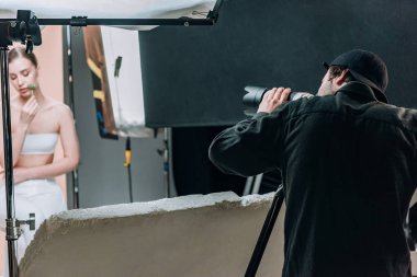 Fotoğraf stüdyosunda spot ışıklarıyla fotoğraf çeken seçici kameraman ve çekici model.