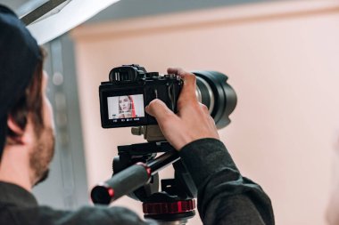 Selective focus of videographer looking at female model on camera display clipart