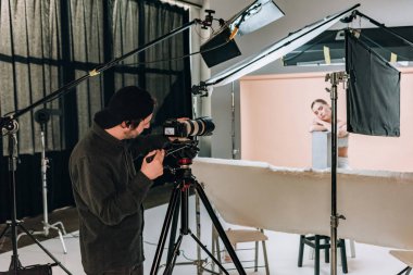 Fotoğraf stüdyosunda spot ışıklarıyla çekici bir model çeken kameraman.