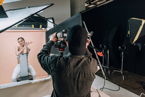 Beautiful smiling model posing to videographer with camera in photo studio