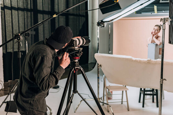 Cameraman filming beautiful woman in photo studio 