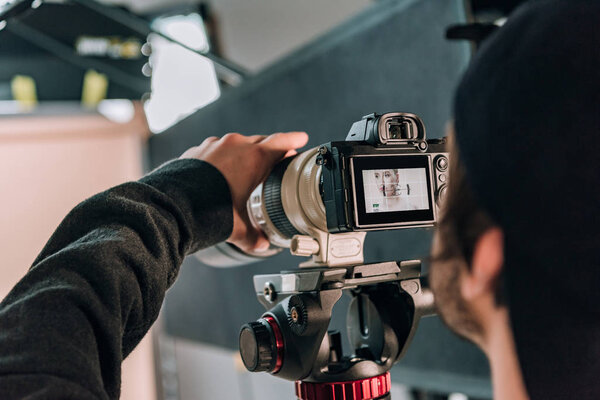 Selective focus of videographer filming woman in photo studio