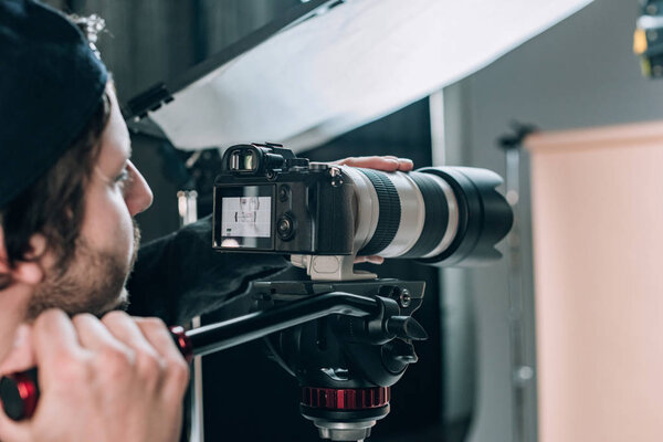 Selective focus of videographer filming beautiful woman in photo studio