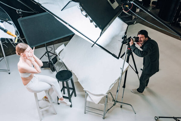 Overhead view of beautiful model and videographer working in photo studio with spotlights