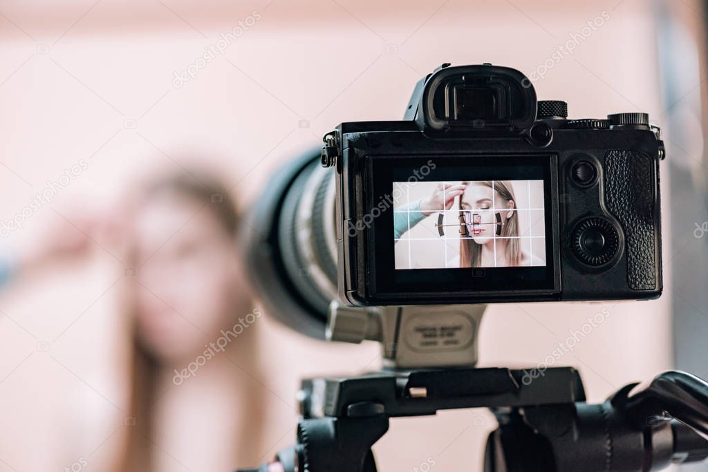 Selective focus of assistant working with attractive model on camera display in photo studio