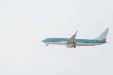 Arka planda bulutlu gökyüzü ile havalanan uçağın alçak açılı görüntüsü
