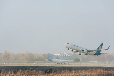 Commercial plane taking off from airport runway with cloudy sky at background clipart