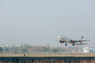 Jet plane above airport runway with cloudy sky at background clipart