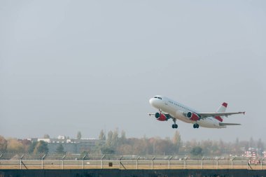 Airplane taking off from airport runway with cloudy sky at background clipart