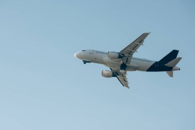 Mavi gökyüzünde uçan ticari uçağın alçak açılı görüntüsü