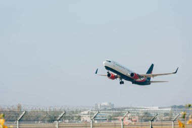 Arka planda mavi gökyüzü olan bir jet uçağı havaalanı pistine iniyor.