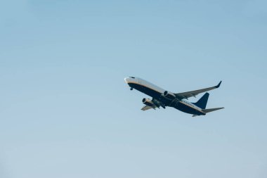 Mavi gökyüzünde havalanan uçağın alçak açılı görüntüsü