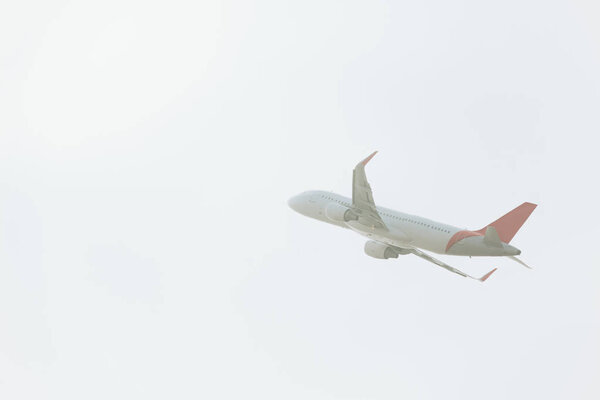 Low angle view of commercial plane taking off in cloudy sky