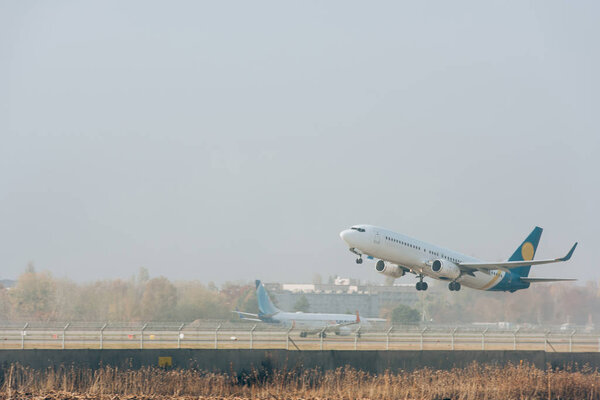 Коммерческий самолет взлетает с взлетно-посадочной полосы аэропорта с облачным небом на заднем плане
