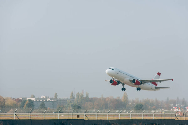 Самолет взлетает с взлетно-посадочной полосы аэропорта с облачным небом на заднем плане
