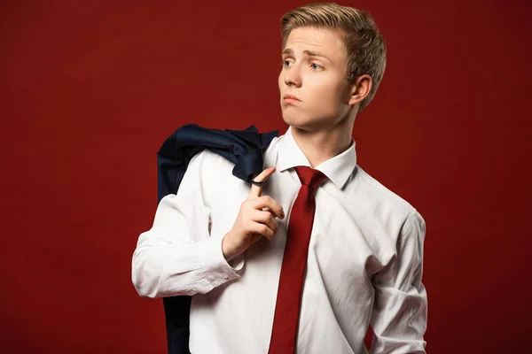 Homme confiant avec veste sur le doigt sur fond rouge — Photo de stock