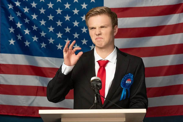 Displeased emotional man on tribune on american flag background — Stock Photo