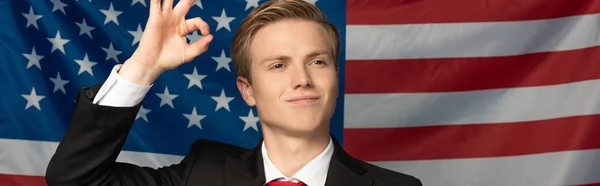 Homme souriant montrant ok signe sur fond de drapeau américain — Photo de stock