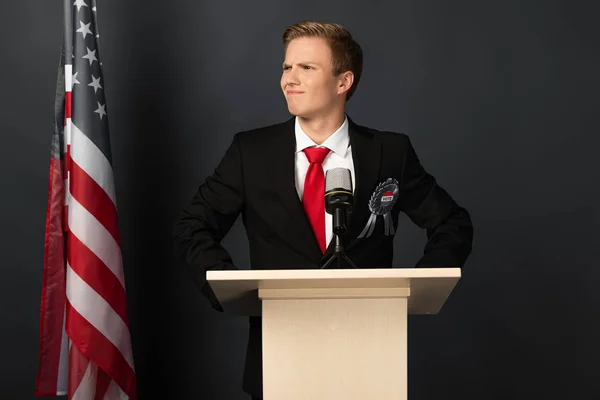 Lächelnder emotionaler Mann auf der Tribüne mit amerikanischer Flagge auf schwarzem Hintergrund — Stockfoto