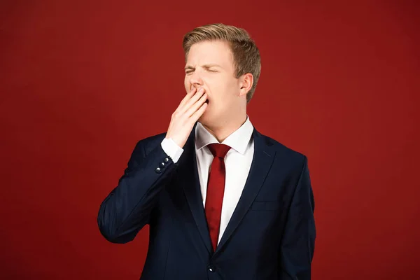 Tired man yawning on red background — Stock Photo