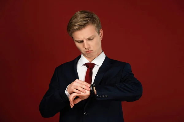 Uomo guardando orologio da polso su sfondo rosso — Foto stock