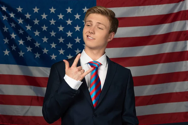 Hombre mostrando gesto de roca sobre fondo de bandera americana - foto de stock