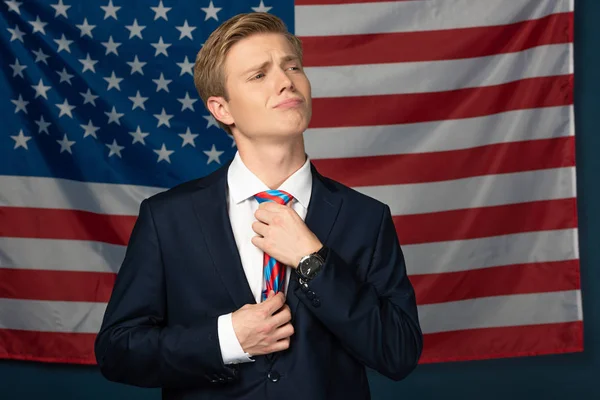 Man fixing tie on american flag background — Stock Photo