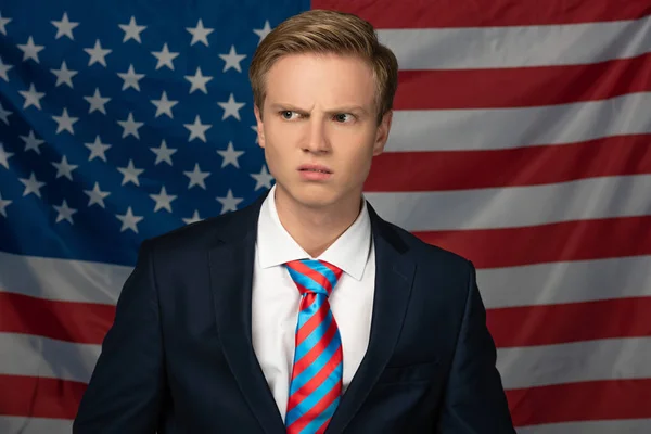 Confundido hombre mirando hacia otro lado en fondo de la bandera americana - foto de stock