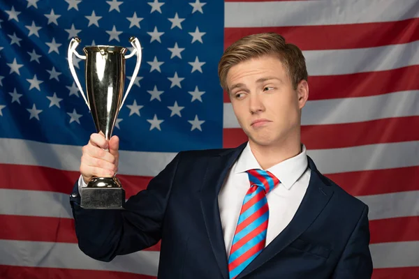 Uomo in possesso di calice d'oro su sfondo bandiera americana — Foto stock