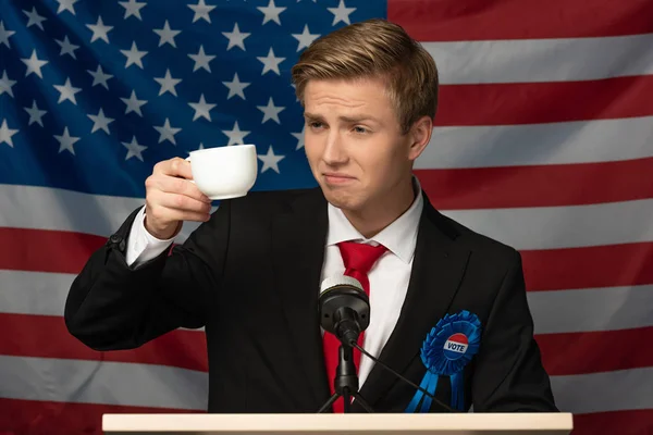 Hombre beber café en tribuna en american bandera fondo - foto de stock