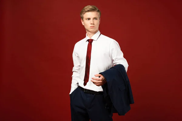 Man standing with hand in pocket and blazer on red background — Stock Photo