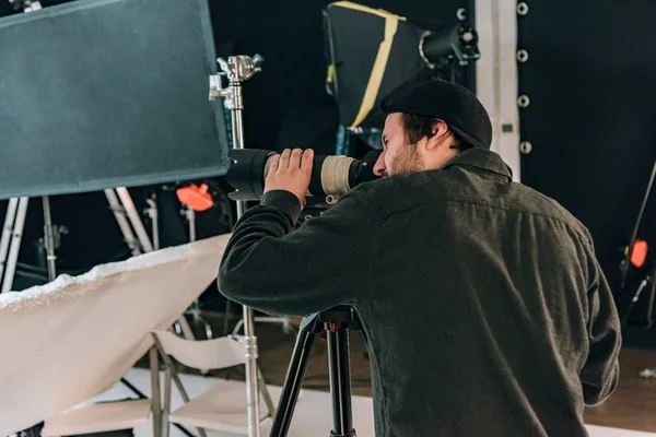 Vista lateral do videógrafo com câmera e refletores em segundo plano — Fotografia de Stock