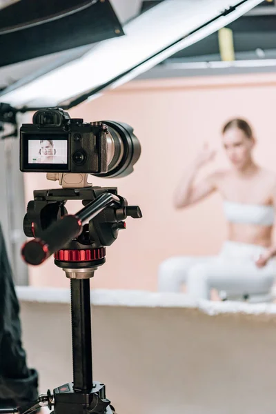 Concentration sélective de la femme posant à la caméra vidéo dans le studio photo — Photo de stock