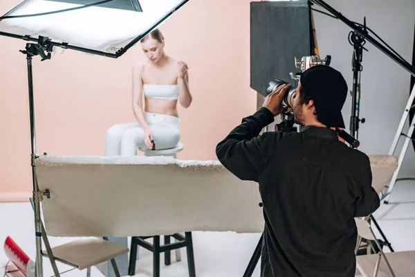 Videographer with camera filming beautiful model in photo studio — Stock Photo