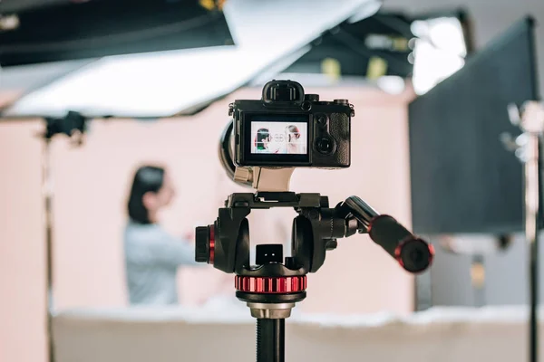 Enfoque selectivo del modelo y asistente femenino reflejándose en la pantalla de la cámara en el estudio fotográfico - foto de stock