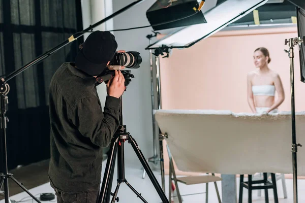 Enfoque selectivo del videógrafo filmando hermosa modelo femenina en estudio fotográfico - foto de stock