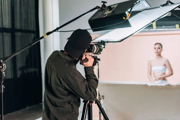 Selective focus of cameraman working with beautiful model in photo studio — Stock Photo