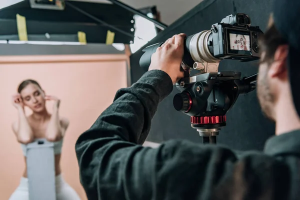 Concentration sélective du caméraman et beau modèle travaillant en studio hoto — Photo de stock