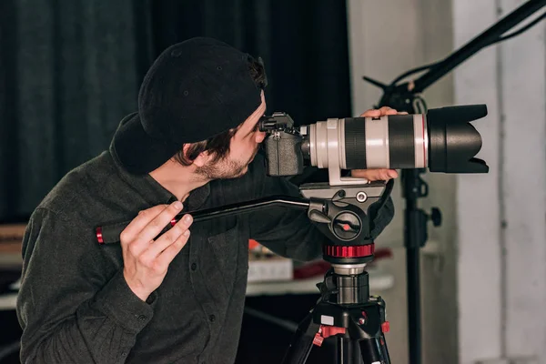 Seitenansicht des Videofilmers bei der Arbeit mit der Kamera im Fotostudio — Stockfoto