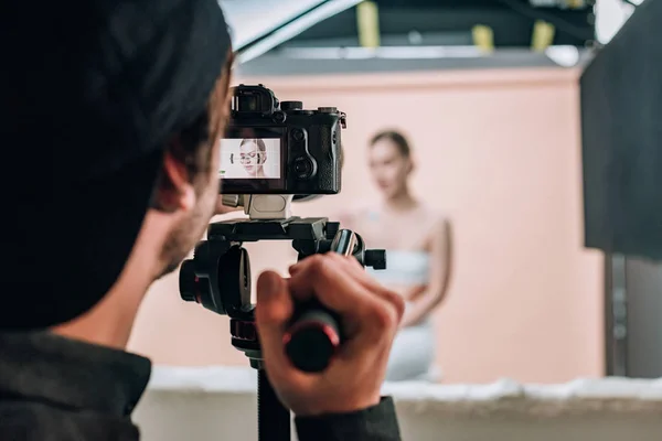 Foco seletivo do videógrafo olhando para a exibição da câmera enquanto trabalha com o modelo — Fotografia de Stock