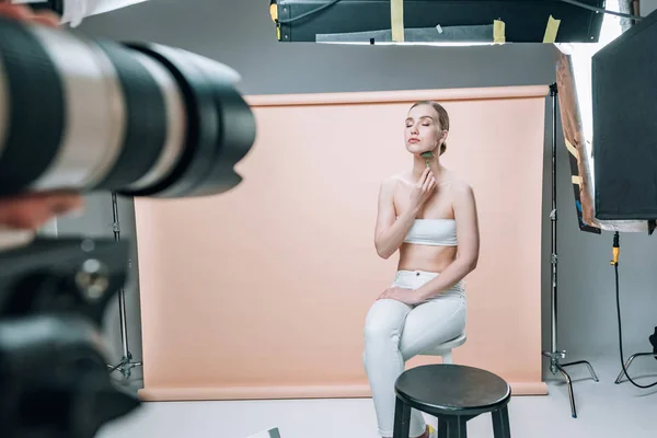 Selective focus of beautiful model holding massage roller while posing to videographer in photo studio — Stock Photo