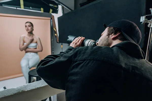 Enfoque selectivo del videógrafo filmando modelo femenina en estudio fotográfico - foto de stock