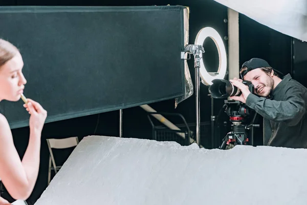 Selective focus of videographer shooting beautiful model with massage roller in photo studio — Stock Photo