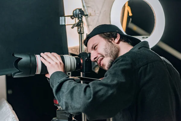 Vista laterale del bellissimo cameraman che lavora in studio fotografico — Foto stock