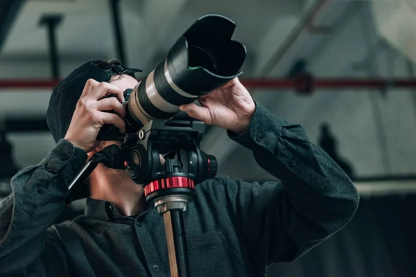 Low angle view of videographer with camera on tripod in photo studio — Stock Photo