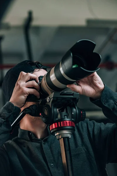 Visão de baixo ângulo do videógrafo olhando através do visor da câmera — Fotografia de Stock