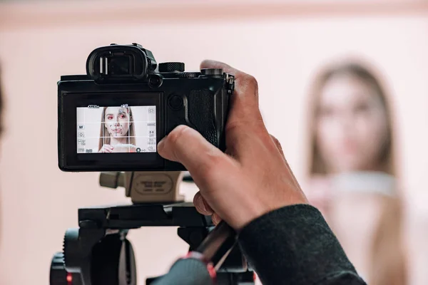 Selective focus of videographer working with attractive model in photo studio — Stock Photo