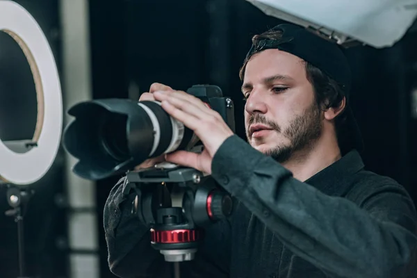 Красивий відеооператор дивиться на дисплей фотоапарата в фотостудії — стокове фото
