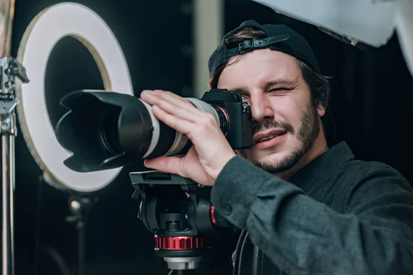 Videógrafo mirando en visor de cámara en estudio fotográfico - foto de stock